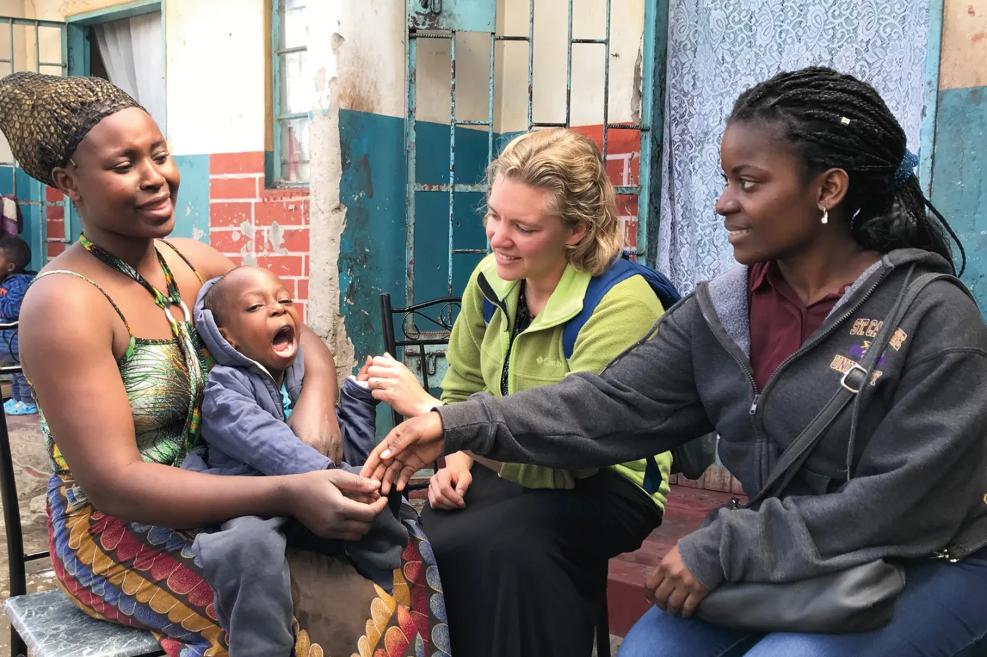 Nursing student Erica Carlson '19 (second from right) and public health student Sabrina Kubisa '22 (right) speak with a mother and young child as part of their work with the Catholic Medical Mission Board and the Kumasala+ Project in Zambia.