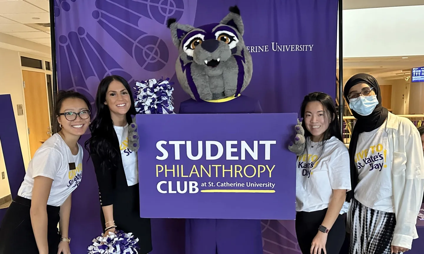 Students and staff gather with the Wildcat mascot and a sign that reads, "Student Philanthropy Club"