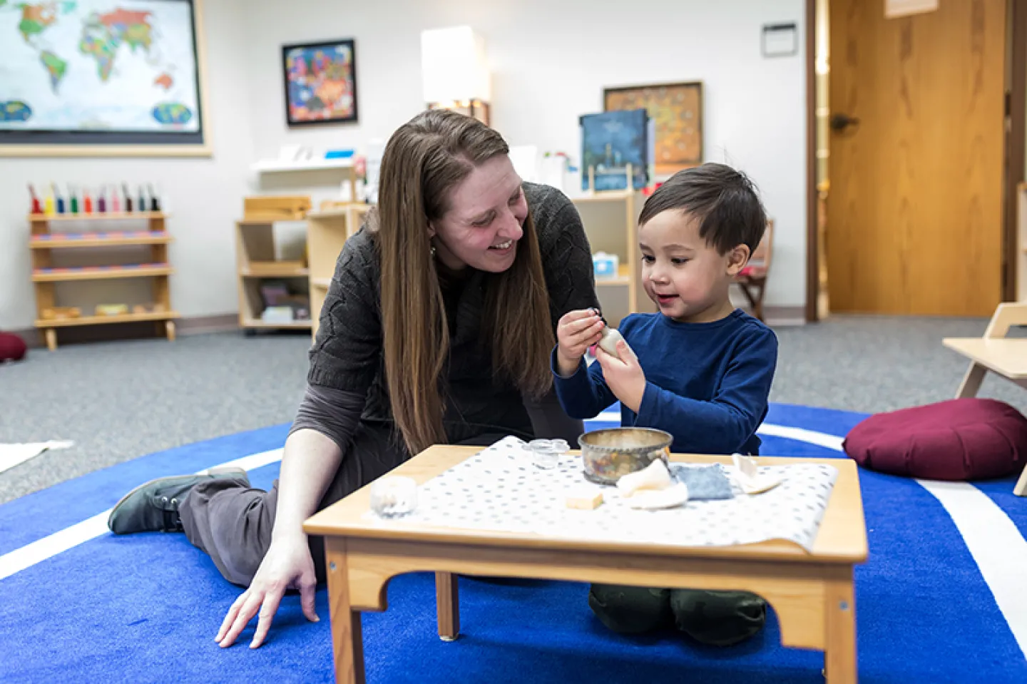 Student working with child in Montessori classroom.