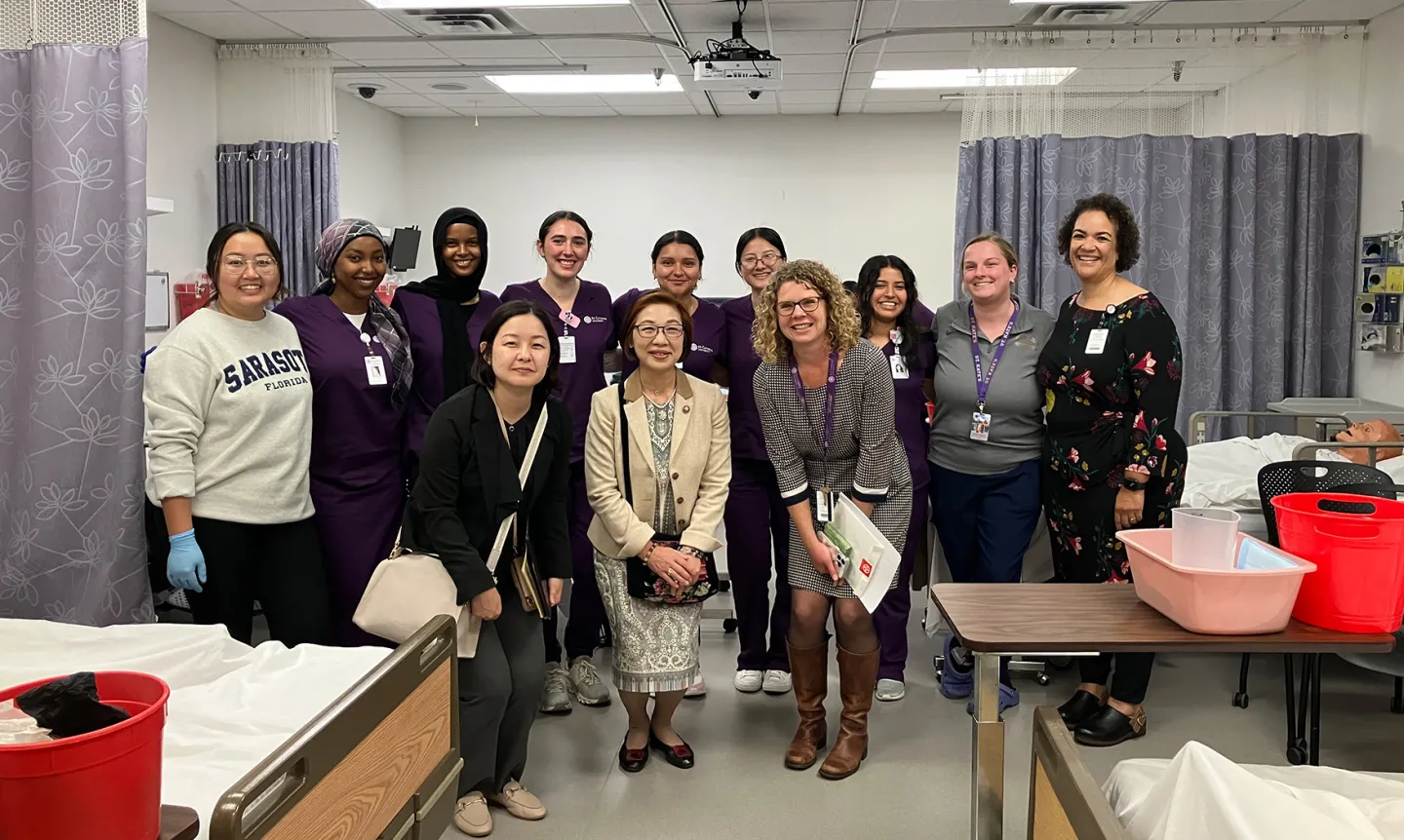 Two faculty members from Kansai Medical University pose with St. Kate's faculty and staff in thee simulation lab.