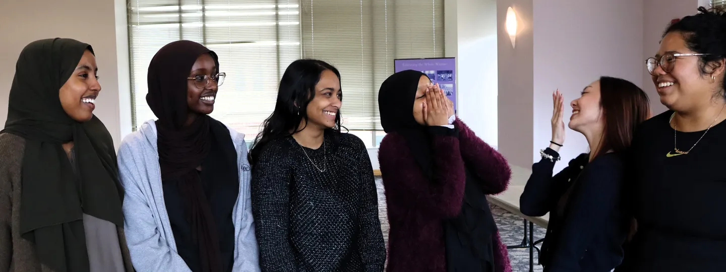 Six female students standing together and talking.