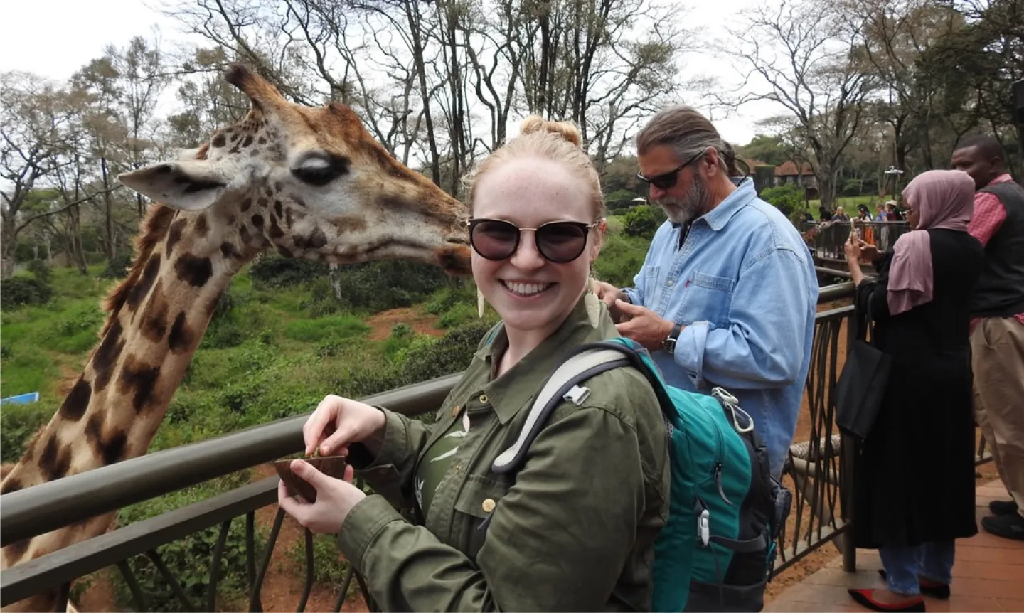 Laura Schulz stands next to a giraffe
