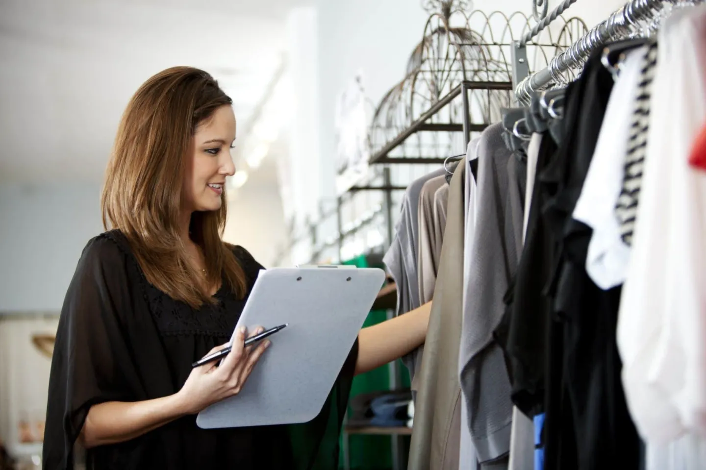 Retail store employee looking at inventory of women's clothes