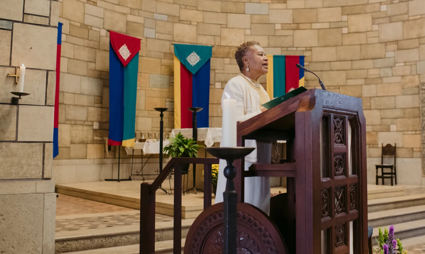 President Evans, wearing white, stands at the pulpit in the Chapel.