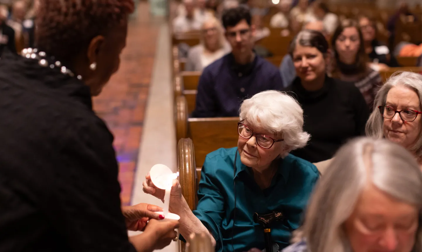 President Evans lights community members' candles during the 2024 Feast of Saint Joseph prayer service