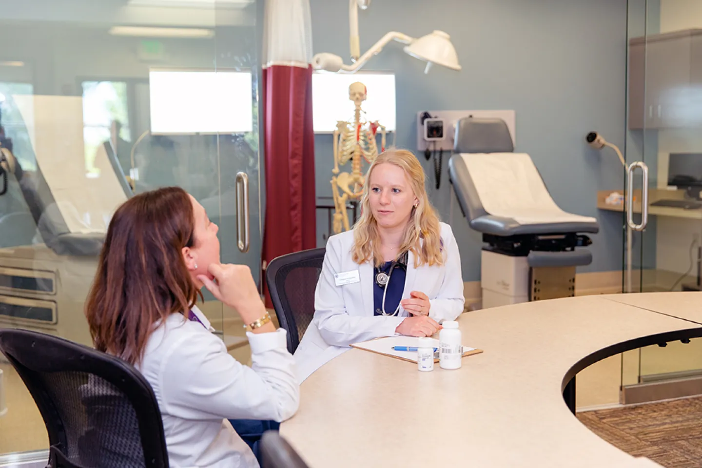 Nursing student and nursing instructor sitting at at table discussing a scenario