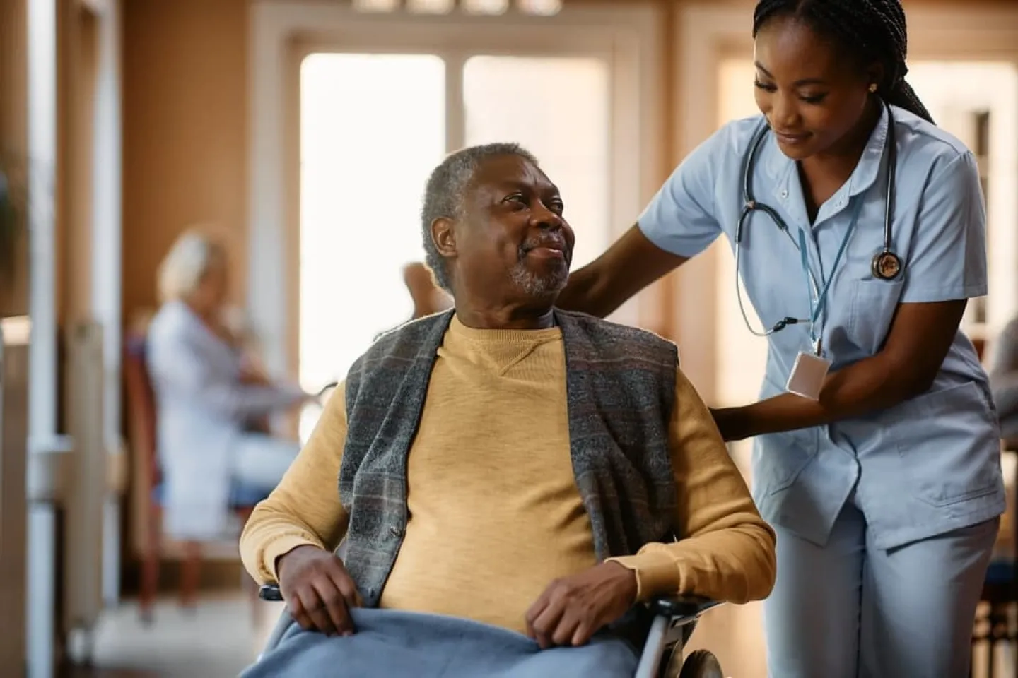 A nurse helps a senior African-American man in a wheelchair