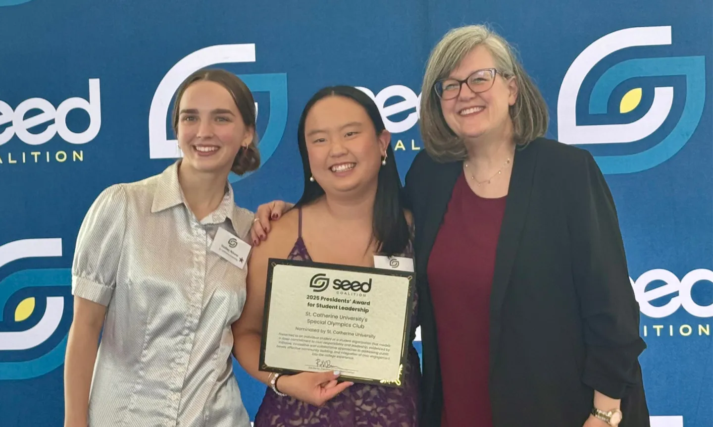 Two students pose with a certificate next to the Seed Coalition board chair.