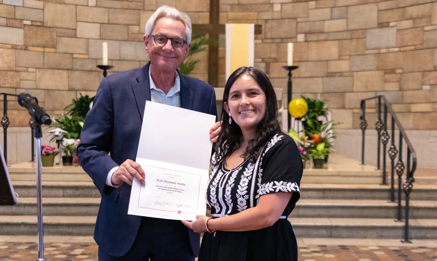 Two people stand in front of an altar, holding a paper certificate between them.