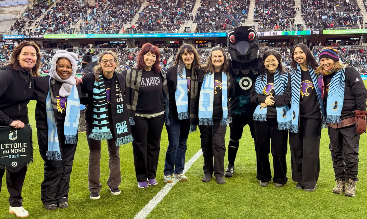 St. Kate's staff and students pose with the Loons mascot on the Minnesota United soccer field.