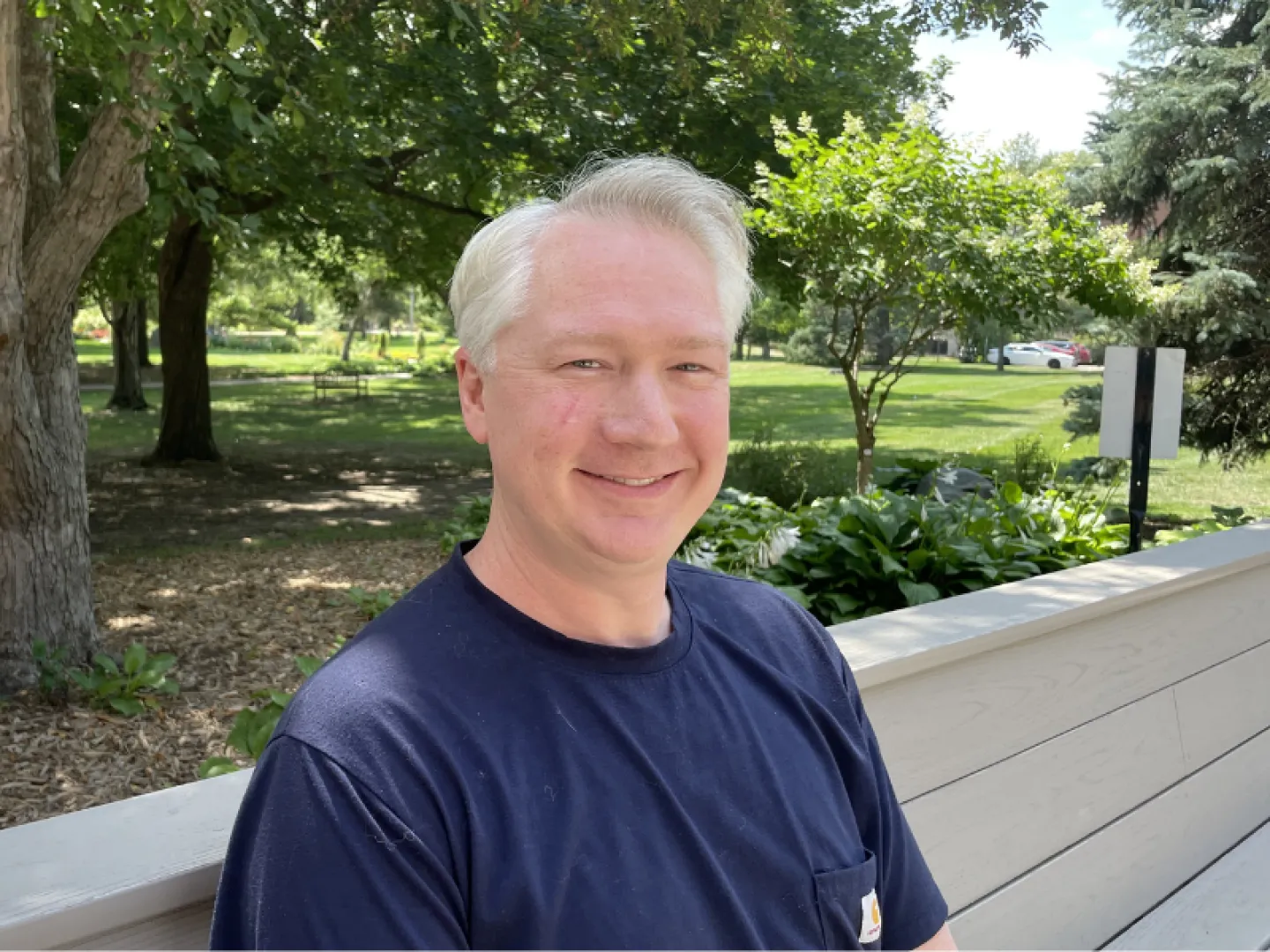 white male with white hair wearing a blue tee shirt