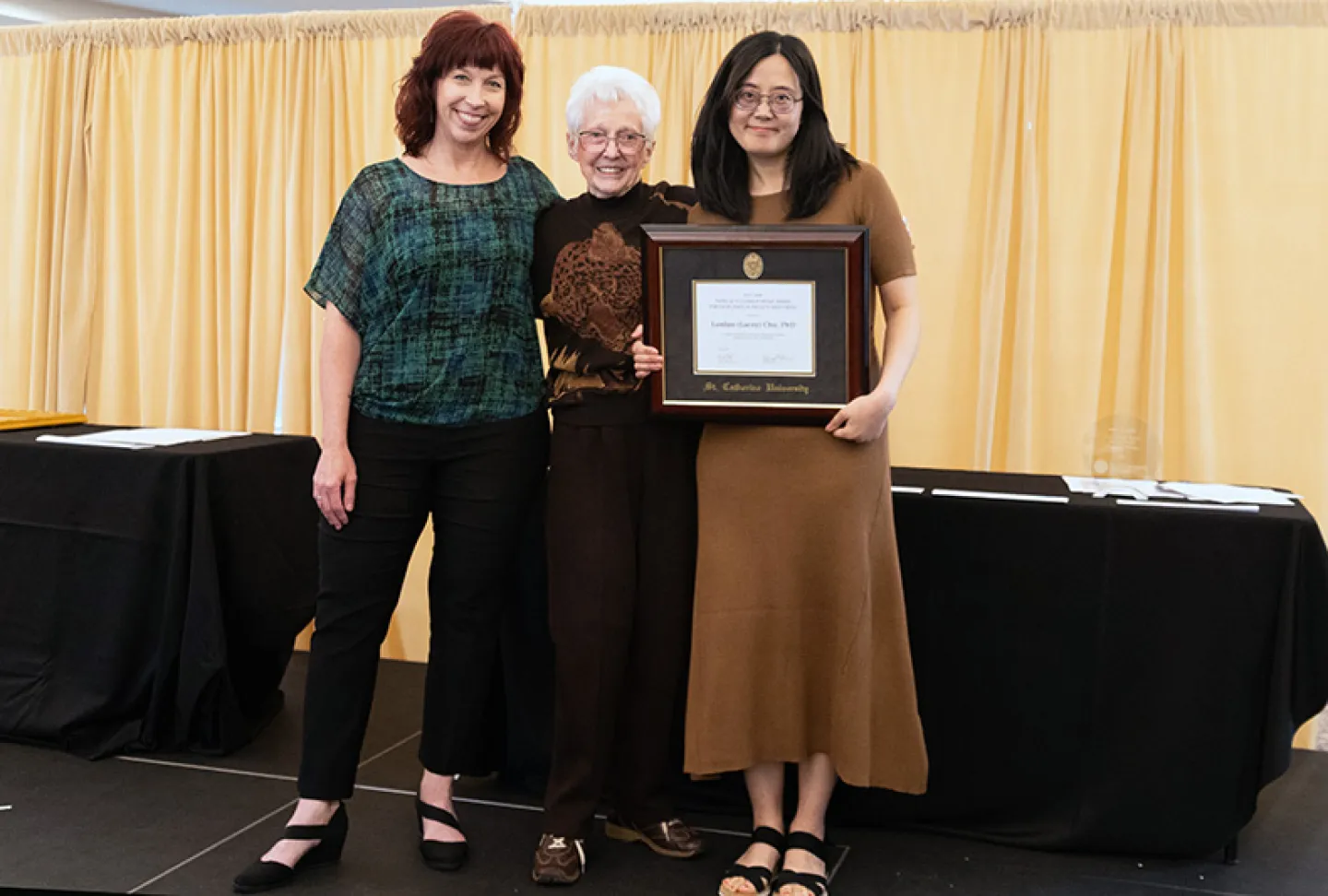 Myser award winner holding plaque and posing with Patricia Myser and the co-presenter